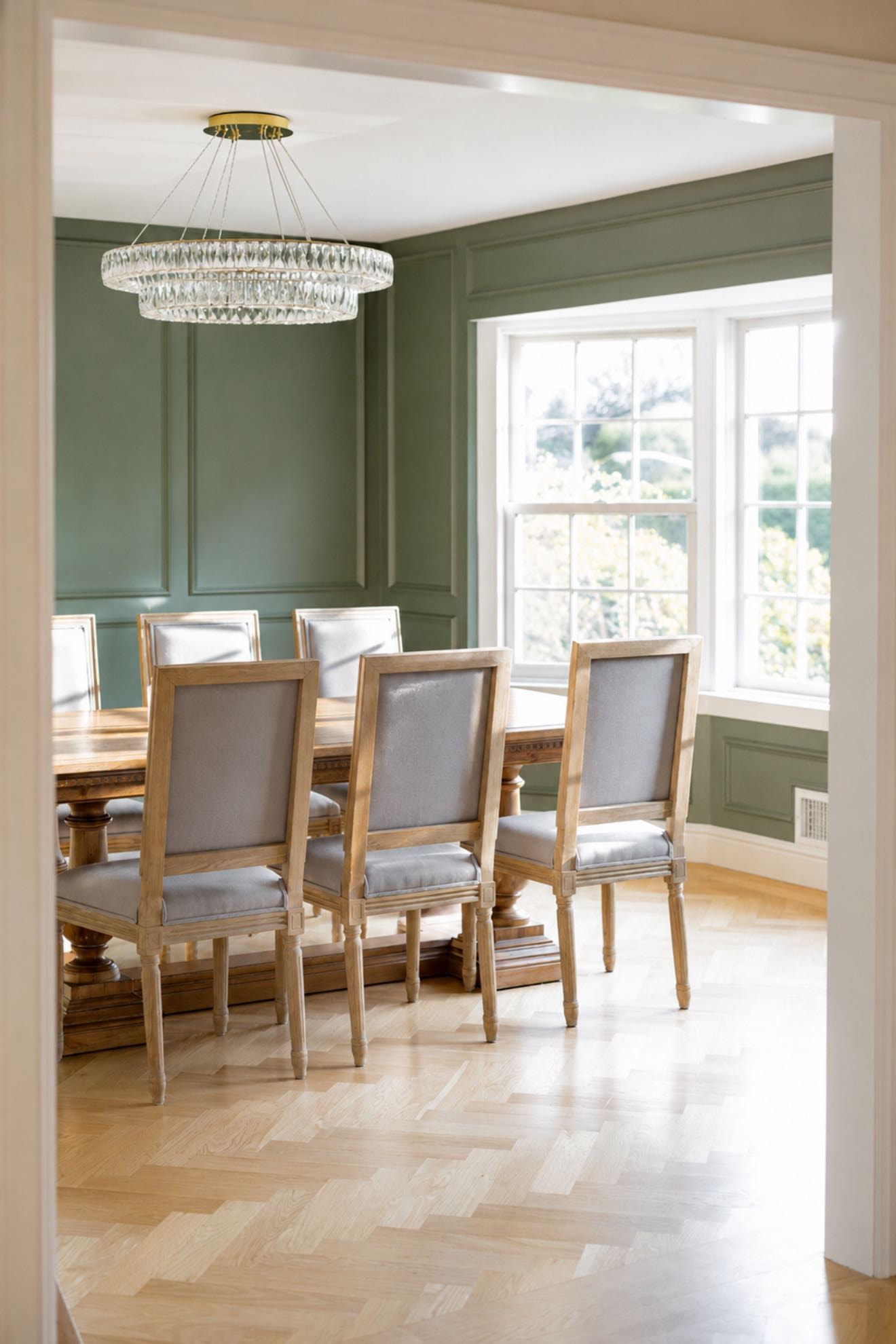 Elegant dining room with sage green walls and crystal chandelier